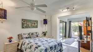 Een slaapkamer met een bed, nachtkastje, lamp en kunstwerk.