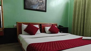 Un lit avec une couette rouge, deux oreillers rouges et une tête de lit en bois.