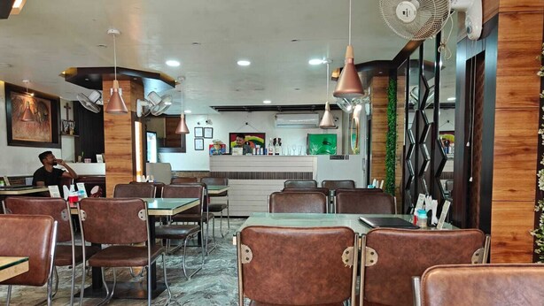 L’intérieur d’un restaurant, avec des banquettes, des tables et un comptoir.