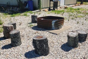 A metal fire pit surrounded by wooden stumps and gravel. - Hike & Fish! Ozarks Studio on Multi-Unit Farm (Richland)