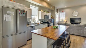 A modern kitchen with stainless steel appliances, a wooden island, and a grey sofa in the living area. - Richland Home on Multi-Unit Farm: Fish, Hike! (Richland)