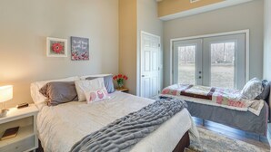 A bedroom with a bed, bedside table, lamp, and a door leading to a balcony. - Richland Home on Multi-Unit Farm: Fish, Hike! (Richland)