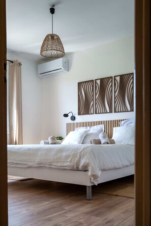 A bedroom with a bed, an air conditioner, a hanging light fixture, and wall art. - Provencal villa Sainte Colombe, swimming pool, view of Mont Ventoux (Faucon)