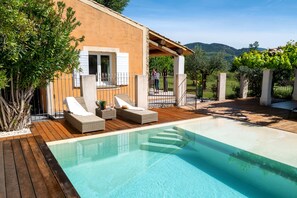 A poolside area with a wooden deck, lounge chairs, and a pergola. - Provencal villa Sainte Colombe, swimming pool, view of Mont Ventoux (Faucon)