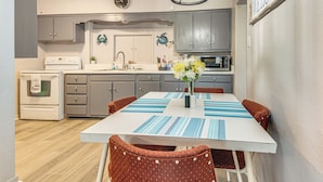 Una cocina con una mesa de comedor, sillas, un reloj y un letrero de bienvenida.