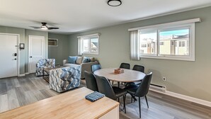 A modern living room with a dining area, a ceiling fan, and large windows. - 2 Blocks to Beach & Boardwalk: Ocean City Condo (Ocean City)