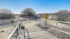A wooden boardwalk leading to a sandy beach area with a wooden fence and a yellow sign. - 2 Blocks to Beach & Boardwalk: Ocean City Condo (Ocean City)