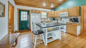 A kitchen with wooden cabinets, a white refrigerator, a microwave, and a dining table with chairs. - Mtn-View Bryson City Cabin: 1 Mi to Deep Creek! (Bryson City)