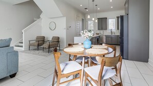Una cucina moderna con zona pranzo, una scala e un soggiorno con divano.