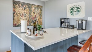 Una cocina con una isla central, una cafetera y un tapiz grande en la pared.