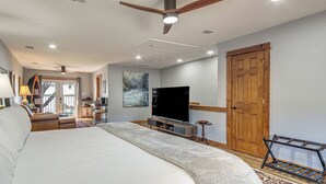 Un dormitorio amplio con una cama grande, una televisión, una puerta de madera y vistas a través de una puerta de cristal.