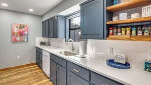 Una cocina moderna con armarios grises, una encimera blanca y suelo de madera.
