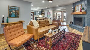 Una sala de estar con sofá, sillón, mesa de centro y chimenea.