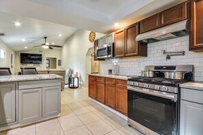 Una cocina con una isla grande, electrodomésticos de acero inoxidable, armarios de madera y un salpicadero de azulejos.