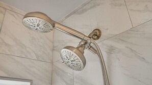 Een douche met een flexibele douchetuit en een vast douchetje, bevestigd aan een betegelde muur.