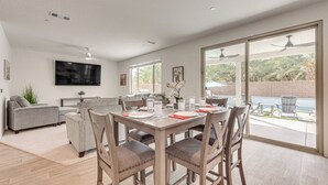 A modern living room with a dining table, chairs, sofas, and a TV mounted on the wall. - 4 Mi to Empire Polo Club: Getaway w/ Outdoor Oasis (Coachella)