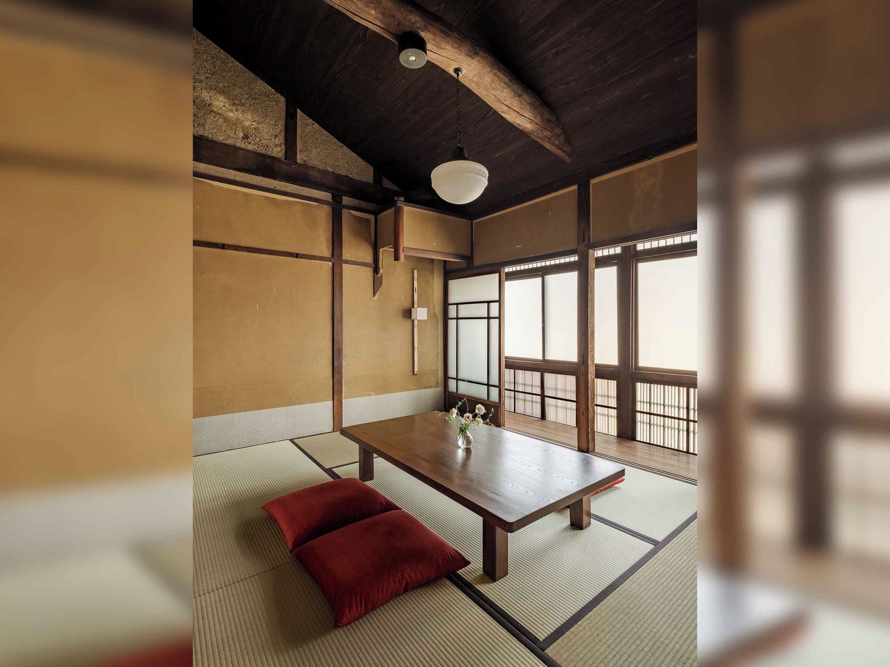 A traditional Japanese room with tatami flooring, a low wooden table, and a view through shoji screens.