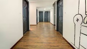 Un pasillo con suelo de madera, paredes blancas y puertas a ambos lados.