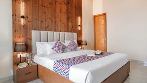 Ein modernes Hotelzimmer mit einer Wandpaneele aus Holz, einem großen Bett mit gemusterten Betttextilien, Nachttischlampen und einer Holztür.