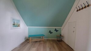 Ein Zimmer mit schrägem Dach, einer Bank, einer Tür und Wandstickern mit Schmetterlingen.