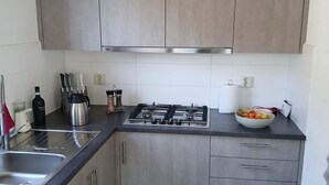 Una cocina con estufa a gas, pileta de acero inoxidable y un cuenco de fruta.