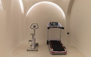 A room with a stationary bike, a treadmill, and a large arched ceiling. - Yangshuo Minos Hotel (Guilin)