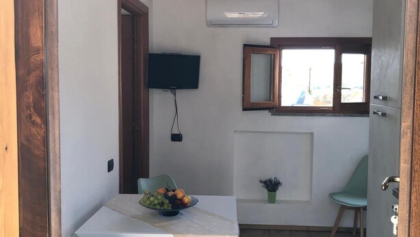 Une cuisine de taille réduite comprenant une table à manger, des chaises, un téléviseur et une fenêtre.