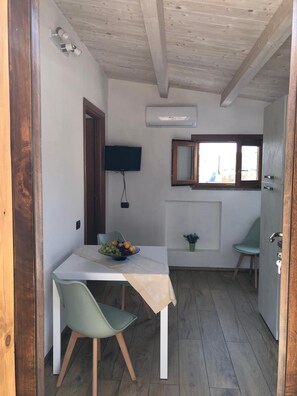 Eine kleine Küche mit Esstisch, Stühlen, Fernseher und Fenster.