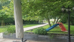 A park with a playground, a pathway, and a lamp post. - Forest Bungalow w/ Sauna for 6 (Ewijk)