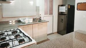Eine Küche mit Gasherd, Spüle, Schränken und Kühlschrank.