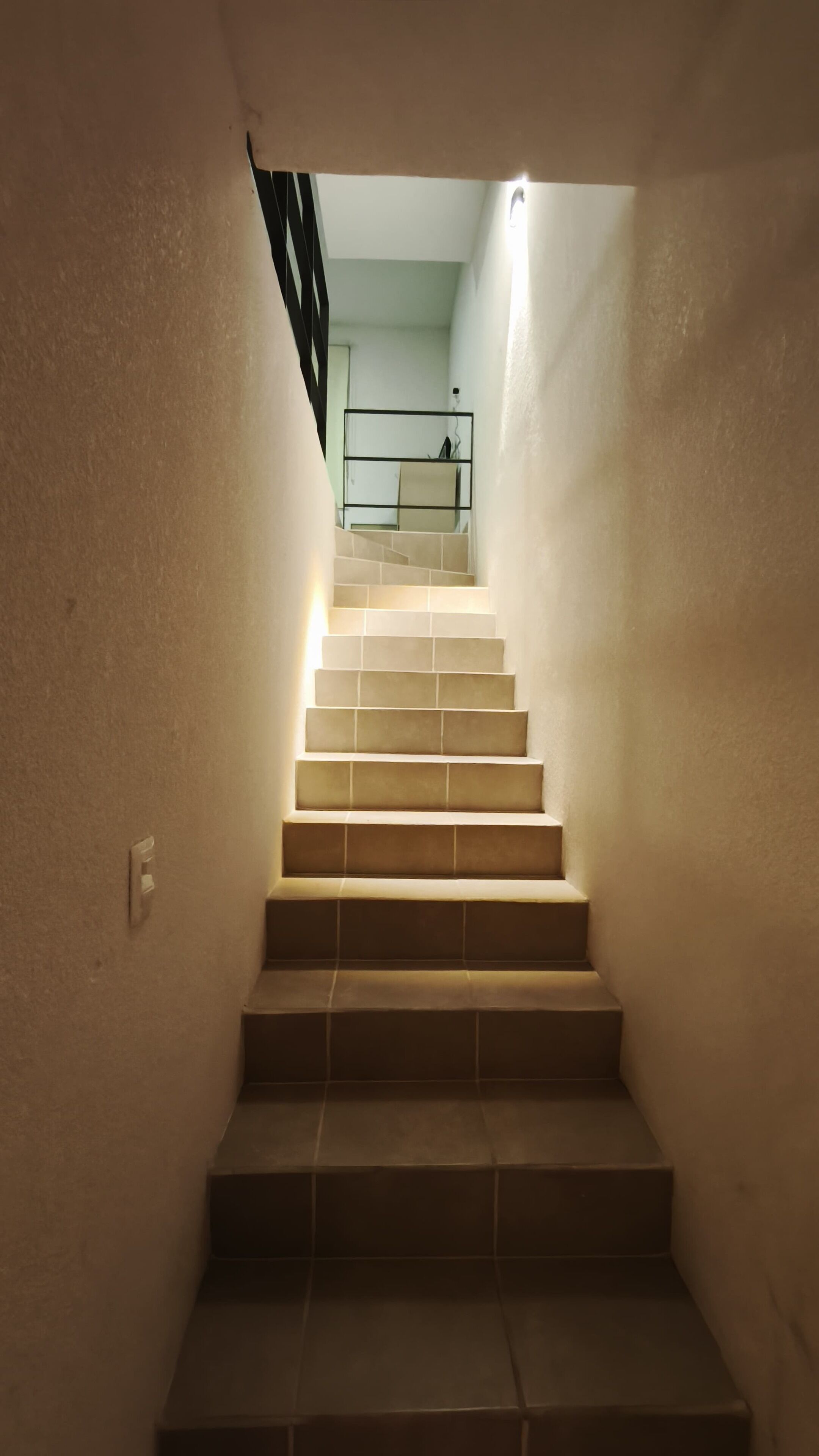 A staircase with a handrail and a light fixture at the top.