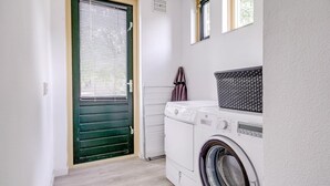 Un cuarto de lavandería con lavadora, secadora y una puerta verde con persianas.