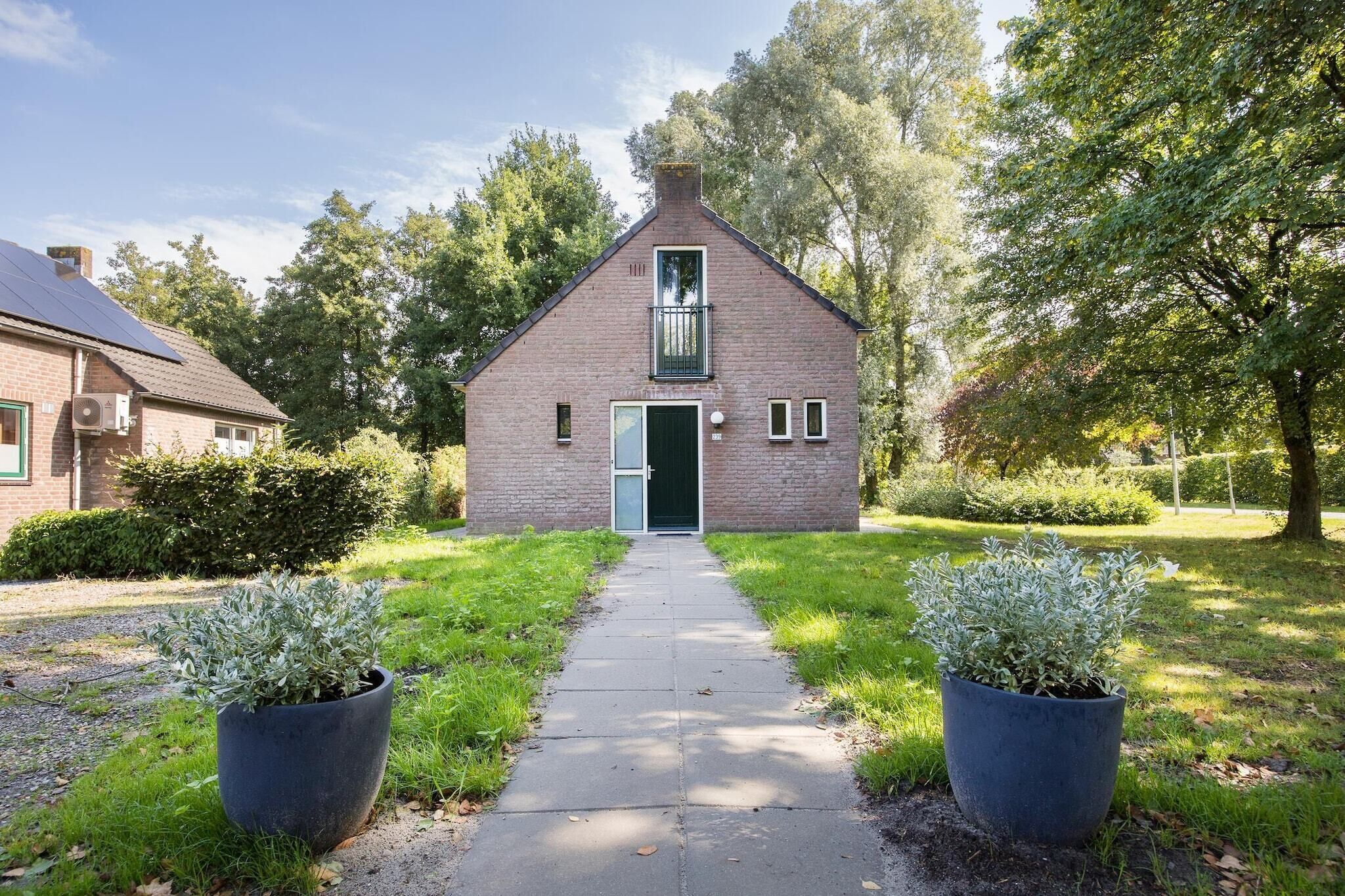Een bakstenen huis met een groene deur, een klein balkon en een verhard pad dat naar de ingang leidt.