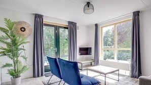 Una habitación moderna con un ventanal grande, un televisor de pantalla plana, una mesa de comedor y una silla azul.