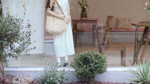 A person standing at a glass door with a view of indoor furniture and plants. - Cotton Castle Hotel - Yangshuo Eternal (Guilin)