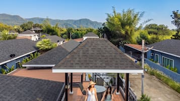 Un barrio residencial con varias casas, una zona de estar al aire libre techada y montañas al fondo.