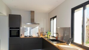 A modern kitchen with a built-in oven, stainless steel range hood, and a large window providing natural light. - Gorgeous Mansion for 6 in Barjac (Barjac)