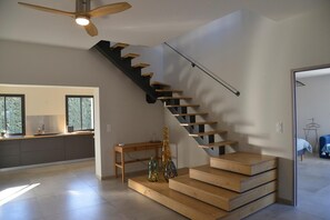 Ein modernes Interieur mit einer Treppe, einer Holzbank und dekorativen Flaschen.