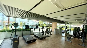 A modern gym with treadmills, weight machines, and a view of the outdoors. - Luxurious One bedroom Condo with Pool View at The Aqua Boat Avenue near Laguna (Tambon Choeng Thale)