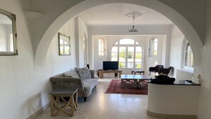 Ein großzügiger Wohnbereich mit Sofa, Couchtisch und Fernseher, mit gewölbten Decken und großen Fenstern.
