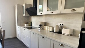 Eine moderne Küche mit weißen Schränken, einem eingebauten Herd, einer Kaffeemaschine und einem Toaster.