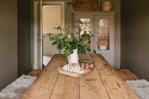 Ein Holztisch mit einer weißen Vase, einem Schneidebrett und einem Drahtkorb.