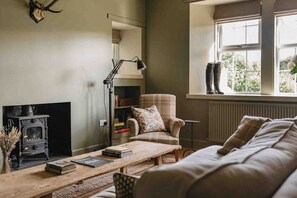 Ein gemütliches Wohnzimmer mit Kamin, einer Couch, einem Couchtisch und einem Fenster mit Blick.