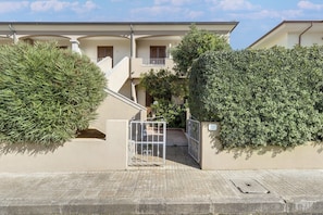 A residential building with a gated entrance, a staircase, and a well-maintained hedge. - Apartment with air conditioning (Tergu)