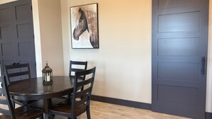 Un comedor con una mesa de madera oscura, sillas, un farol y un cuadro de un caballo en la pared.