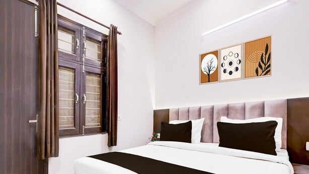 Een slaapkamer met een bed, gordijnen voor het raam, een hoofdeinde en decoratie aan de muur.