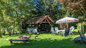 Uma cabana rústica de madeira com varanda, cercada por vegetação exuberante.