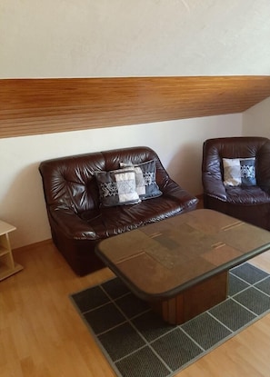 A room with two leather sofas, a wooden coffee table, and a patterned rug.