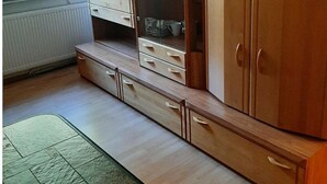 Um quarto com um armário de madeira, um guarda-roupa espelhado e uma mesa de jantar.