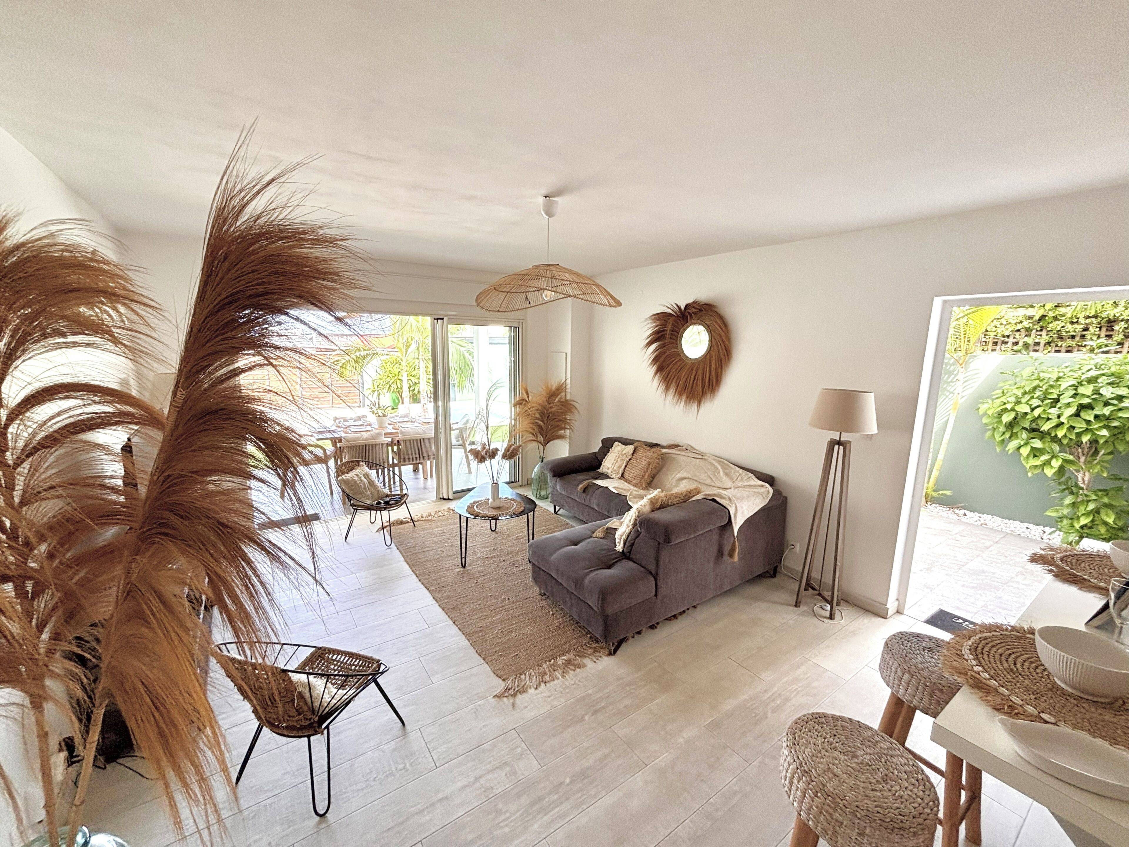 A spacious living area with a sofa, chairs, a coffee table, and a large window with a view of greenery.